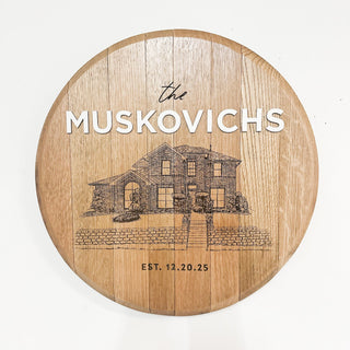 Wooden round cutting board with engraved house illustration and text on a white background
