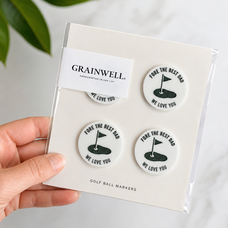 Packaged Golf Ball Markers with 'Grainwell' branding held by a hand.