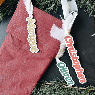 personalized acrylic stocking tags with gold, green, and red paint fills