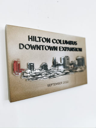 custom gold plaque for hilton columbus downtown expansion with raised acrylic skyline detail
