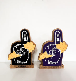 hardwood awards in the shape of a foam finger holding a chicken finger, layered painted details on oak wood, engraved lettering on base