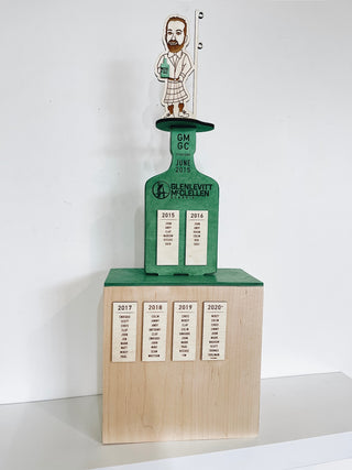 signature wooden award with green painted wood, engraved figure on top, engraved text and wood block platform
