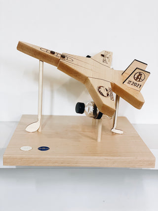 signature wooden award in the shape of an airplane floating above a wooden platform with engraved text 