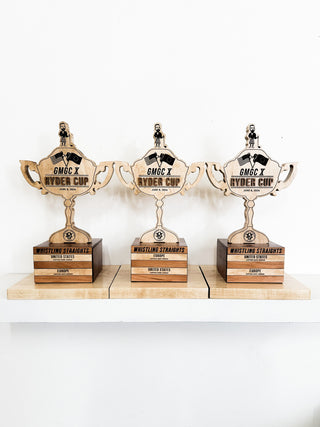 signature wooden awards in the shape of a trophy on a wooden block platform with engraved and raised text