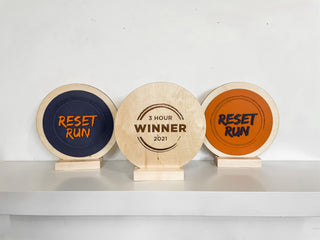 slim wooden award in circular form, with both raised and engraved lettering, blue and orange 