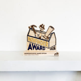 slim wooden award in the shape of a toolbox with engraved details and raised lettering