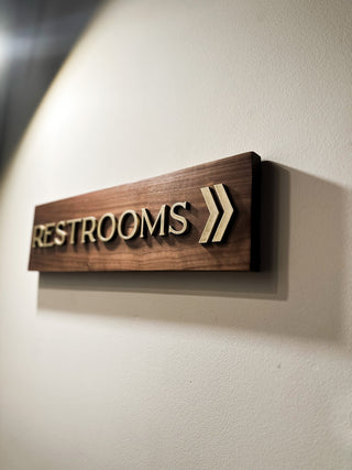 solid walnut wood wayfinding restroom sign with raised gold painted wooden letters