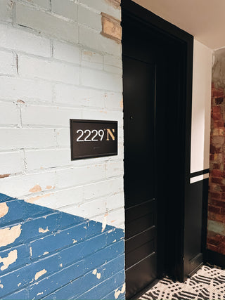 black acrylic sign with raised white acrylic numbers and gold acrylic letter, braille