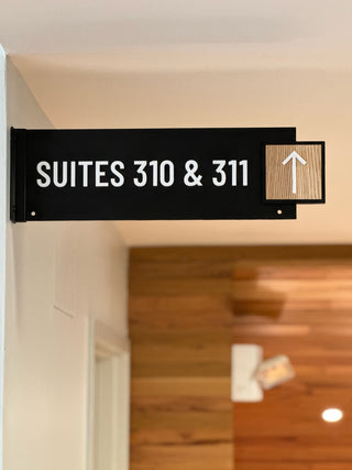black acrylic directional sign with raised white acrylic lettering and wood square with arrow