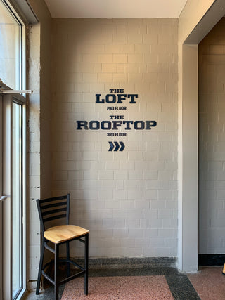 custom wayfinding sign of floating black lettering and arrows on a wall