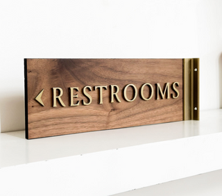 restroom wayfinding sign, wood with raised gold painted wood text and gold hardware 