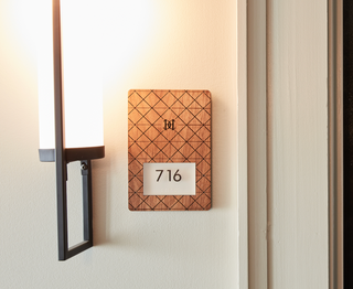 wooden plaque sign with engraved design and white acrylic plaque on top with numbers and braille