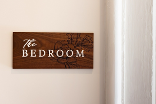 wood plaque directional sign with raised white acrylic lettering and engraved florals