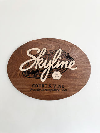 custom oval wood sign with engraved image and text and raised wood skyline 