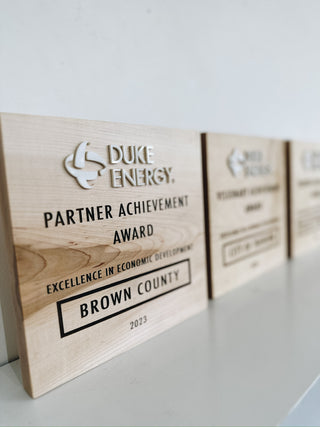 wooden award made from maple with engraved words and raised white acrylic company logo