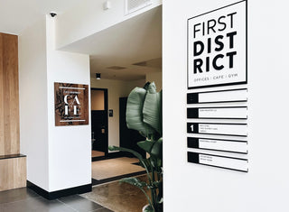 first district cafe wood sign with engraved floral details and first district black and white directional sign 