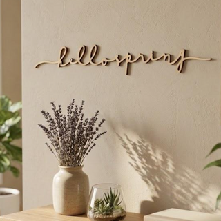 Decorative wall sign with 'hello spring' on a neutral wall with plants and books.