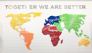 large scale installation of a colorful world map with handwritten names inside and phrase "together we are better" above 