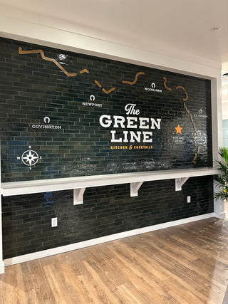 large scale installation of a map to different cities with "the green line" centered, compass in corner