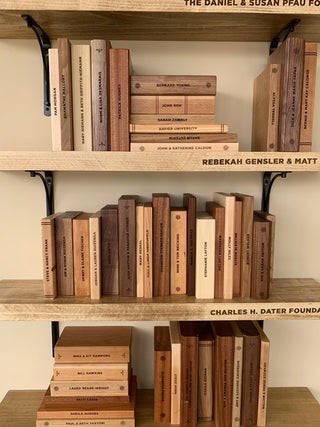 large scale installation of wooden shelves with engraved text and fake wooden books with engraved details and text