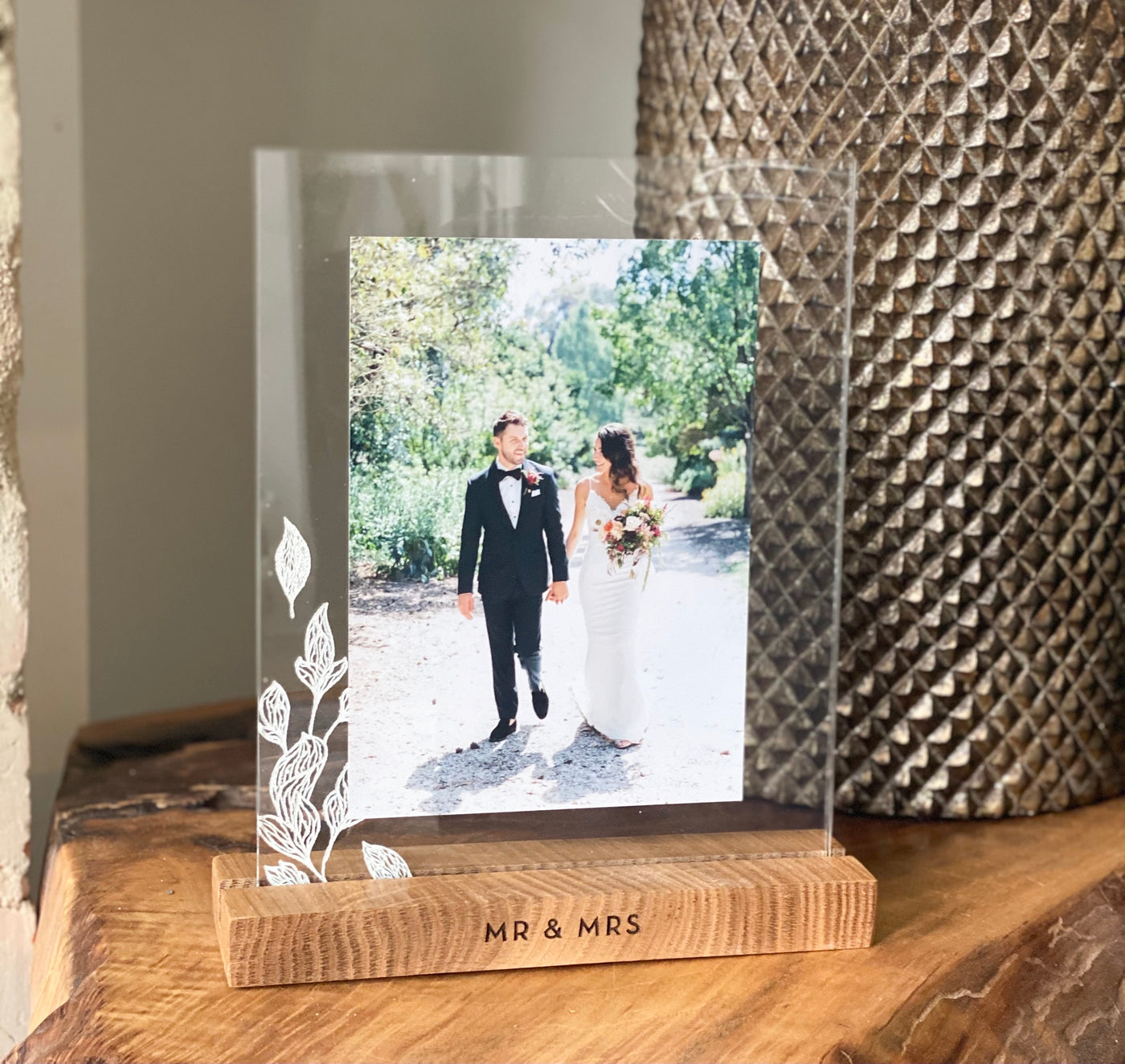 mr & mrs engraved wooden base frame, with 2 acrylic plaques engraved with flowers holding a wedding photo of a couple holding hands. The frame comes in various scripts.